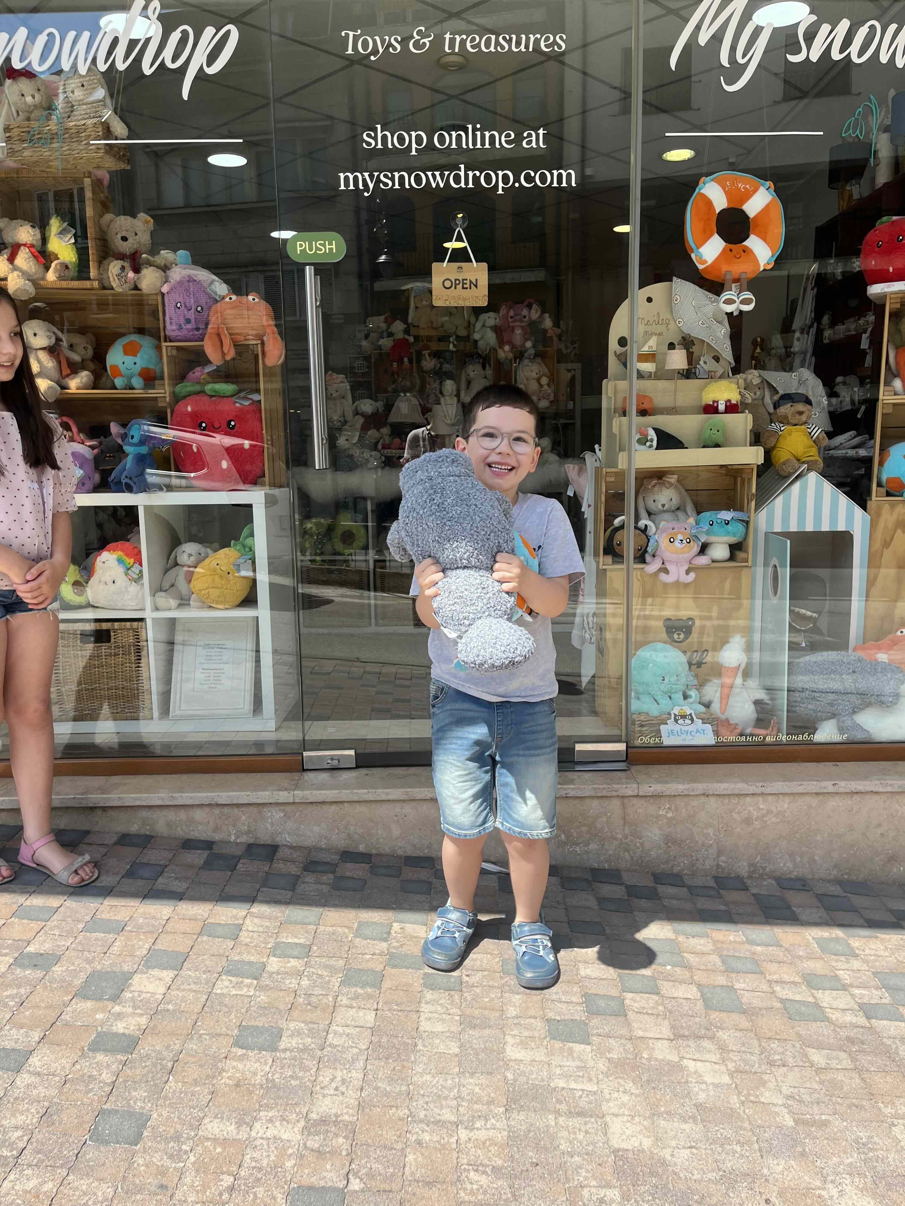 A child holding a plush toy outside the My Snowdrop store in Veliko Tarnovo